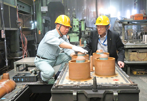 秋田信用金庫が販路拡大を支援したイトー鋳造の本社で、伊藤和宏社長（左）から製品を作る型枠について説明を受ける相原久朝本店長（8月16日）