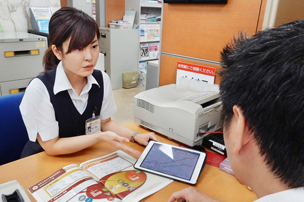 タブレット端末に搭載されたライフプランツールを使って説明する。(８月15日、大分銀行本店営業部個人営業課の担当者)