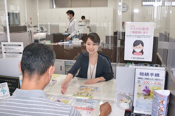 来店客にNISAをPRする桑名三重信用金庫蟹江支店の担当者(６月９日)