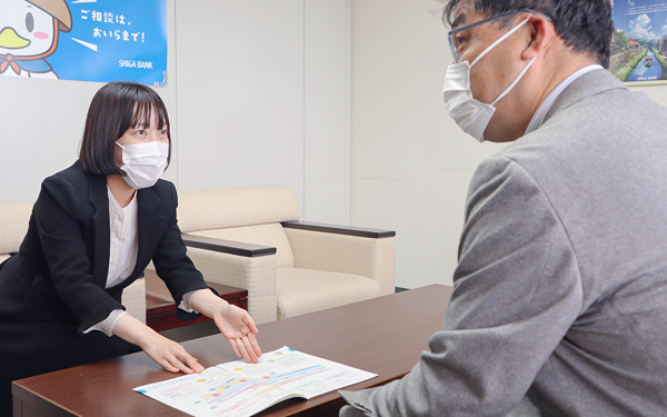来店客(右)に投資手法を紹介する滋賀銀行営業企画グループ主任(５月６日、滋賀銀行本店)