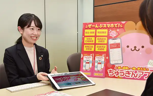 来店客にちゅうぎんアプリの機能を説明する中国銀本店営業部ライフプランアドバイザーの林悠里さん（2月18日、岡山市）