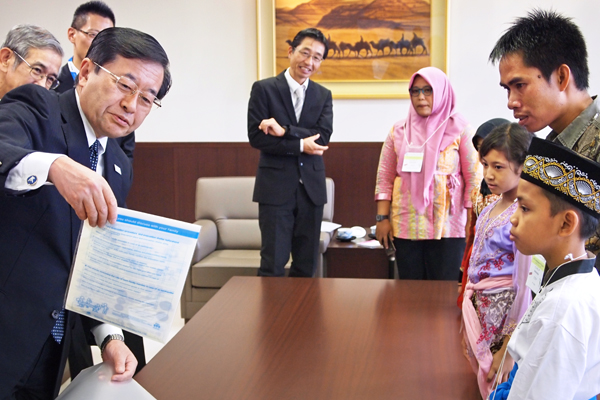 箸や下駄、ノートなど、子供親善大使へのプレゼントを紹介する北沢社長。(左、10月20日)