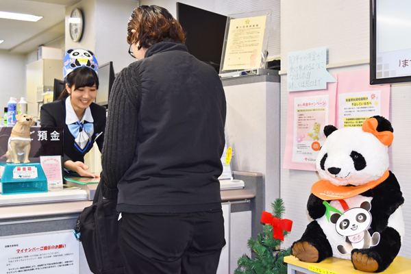 パンダ帽をかぶり「パンダ定期預金」をPRする高橋さん。(12月20日、朝日信用金庫上野支店)