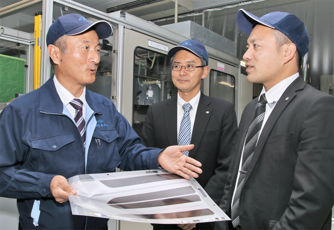 冨士ネームの岩瀬護代表取締役社長（左）に、自動車内装部品の製造工程を聞く清水銀行菊川支店の朝比奈智之支店長（中）と加藤大次渉外長（12月３日、菊川市の冨士ネーム）