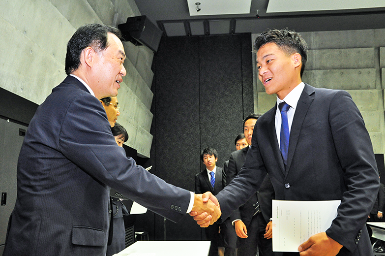 京都銀行の「2019年度入行者内定式」で学生と握手する岩橋俊郎常務取締役（左、18年10月３日、金融大学校）