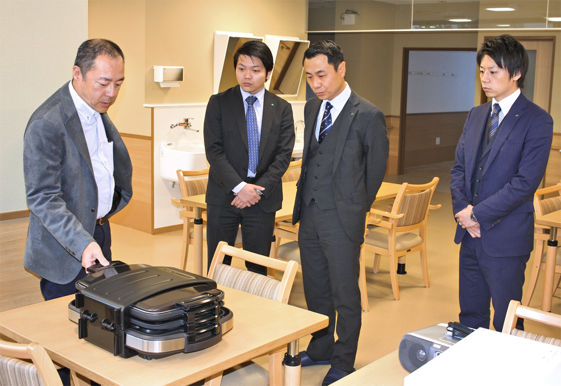 メイン先の一つ、社会福祉法人秀愛会の澤田和秀理事長（左端）から、３月１日オープンの高齢者支援施設「せせらぎの郷」で施設説明を受ける（右から）渉外の西野祥平氏、芝田英樹支店長、渉外の西森大祐氏（２月20日）