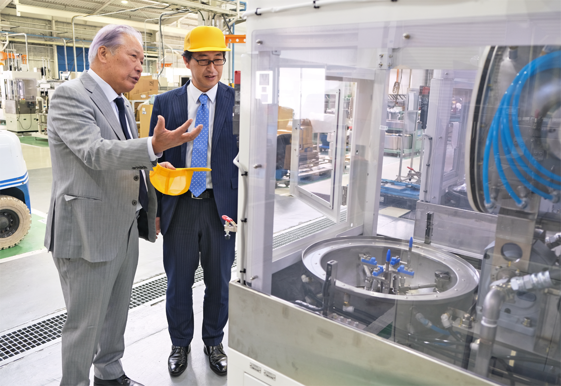 取引先のファインマシーンカタオカの片岡啓二社長(左)から同社が製造する洗浄機の説明を受ける大橋達支店長(4月4日、ファインマシーンカタオカの和泉工場)