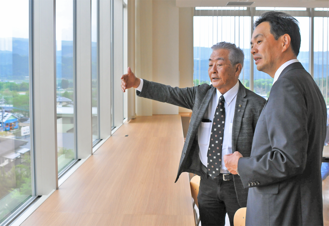 お菓子の香梅の副島隆会長(左)から、4月に完成した新工場を案内される阪田秀規支店長(4月23日、阿蘇郡西原村)