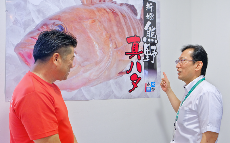 取引先の水谷徹・水谷水産代表取締役(左)と話す東将博支店長(7月24日)