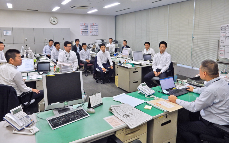 夕礼で各推進リーダーと課長が発表し、案件の進ちょくや実績を共有する（右が渡邊啓一郎支店長、８月７日）