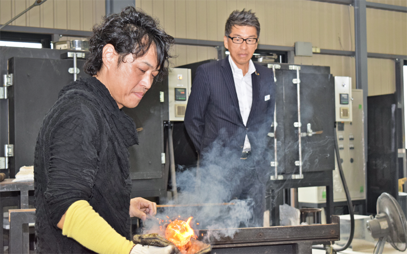 ガラスアーティストである田中英樹氏（左）の制作現場。作業を見つめる松本昭郎支店長（９月26日、工房「アルテラボ」）