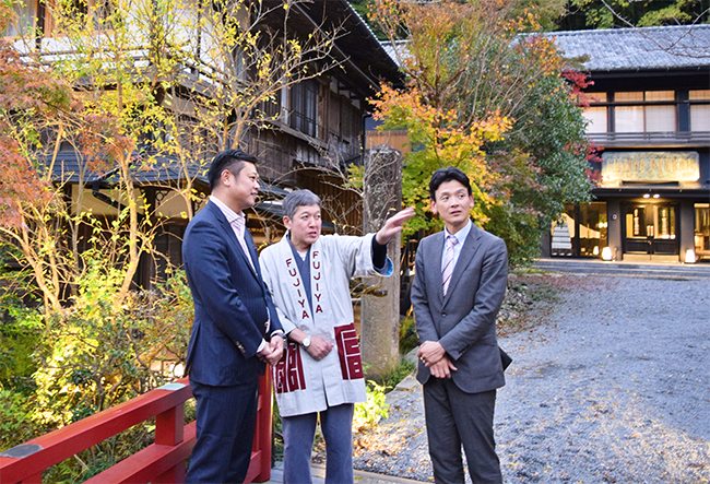 富士屋旅館を前に町の現状について話す（左から）三俣ディレクター、苗代正樹・富士屋旅館支配人、河野グループ長（１９年１２月４日）