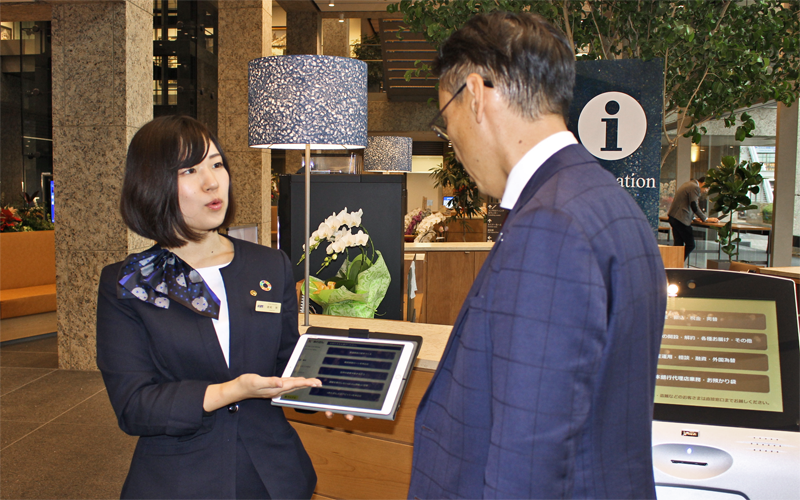 ロビーで来店客の相談に応じるフロアアテンダント(左、2019年12月18日、阿波銀行本店営業部1階)
