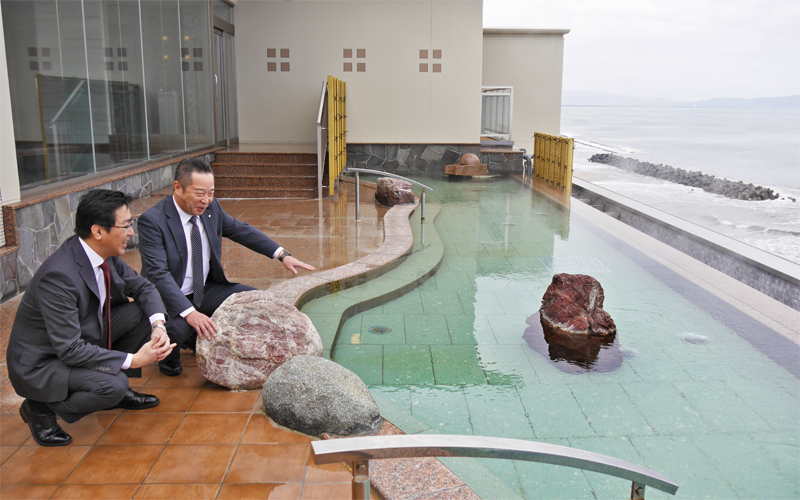 2019年５月にオープンした旅館「游月」を視察して、福元隆司社長（左）から説明を受ける入江到常務執行役員部長（２月19日）