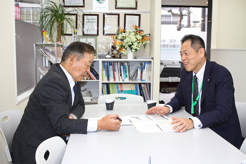 主要取引先の福井住宅流通の間政和社長(左)に提案活動を行う小坂祥久支店長