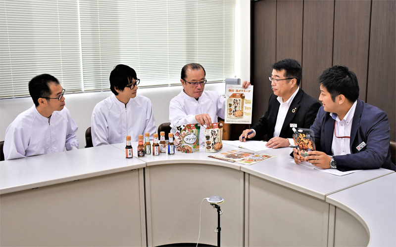 取引先の技術力などの強みは日頃の訪問活動で把握。工場関係者から製品や品質管理について説明を聞く仲本範之支店長(右から2人目)と檜垣和宏主任(右、10月21日、仙味エキス)<写真撮影時にマスクを外していただきました>