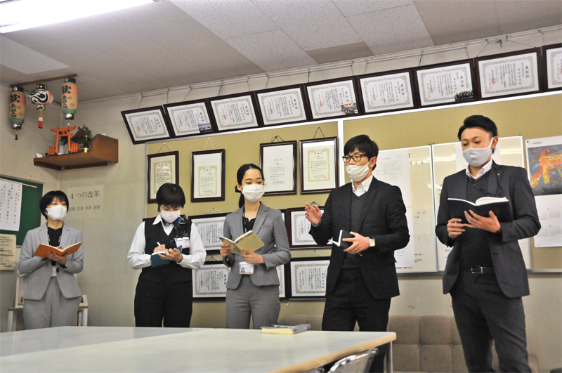朝会で自身が受講したコンサルティング研修の要点を解説する上床智哉主任(右から2人目、1月14日)