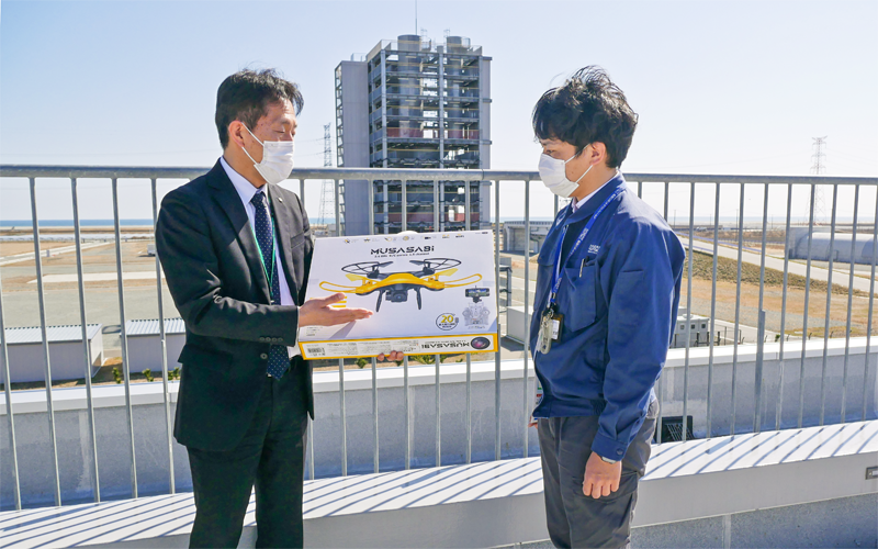 ドローンについて会話する(左から)あぶくま信金の木村繁夫業務推進部副部長と福島イノベーション・コースト構想推進機構の平賀大輔事業部副主査(3月9日、福島ロボットテストフィールド)