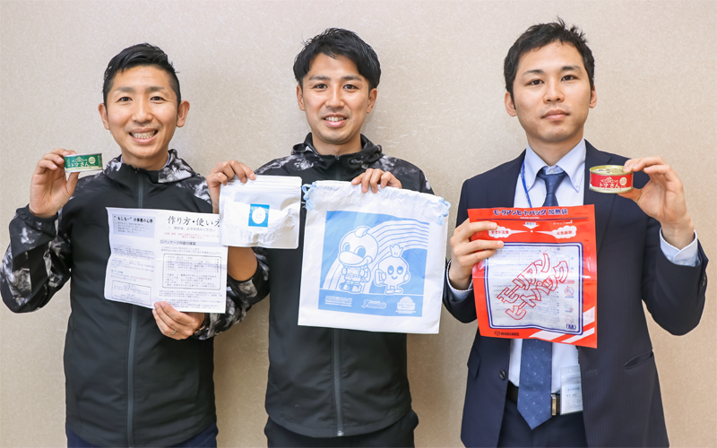 食事セットを手にする担当者たち(3月26日、川崎信金本部)