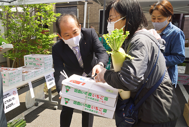 即売会では鹿沼相互信用金庫の協力で栃木県鹿沼市産イチゴ「とちあいか」も出品・完売。買い物客を手伝う土屋理事長(4月15日)