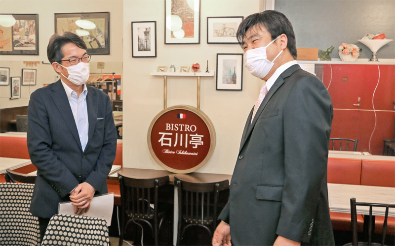 洋食屋「ビストロ石川亭」を運営する石川敏樹社長(右)にコロナ禍の経営について情報交換する小泉直哉支店長(5月20日、東京都)