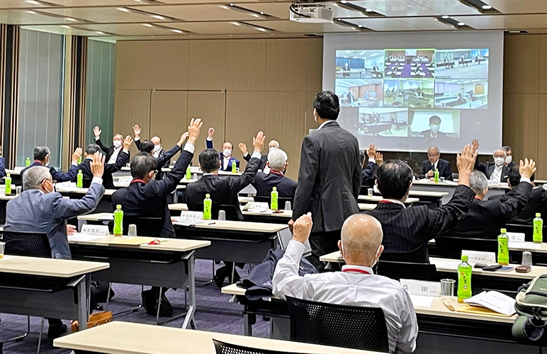 ウェブ会議システムでつないだ地区会場ごとに議案の賛否を挙手で確認した（6月29日、全国信用組合会館）