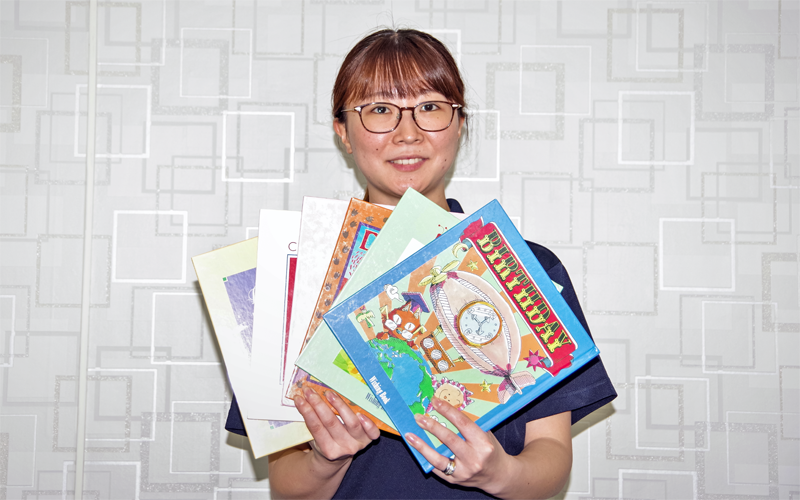「ベビーブック」「バースデー」「クリスマス」など6種類の絵本を持つ理事長秘書(8月19日、新庄信金本部)