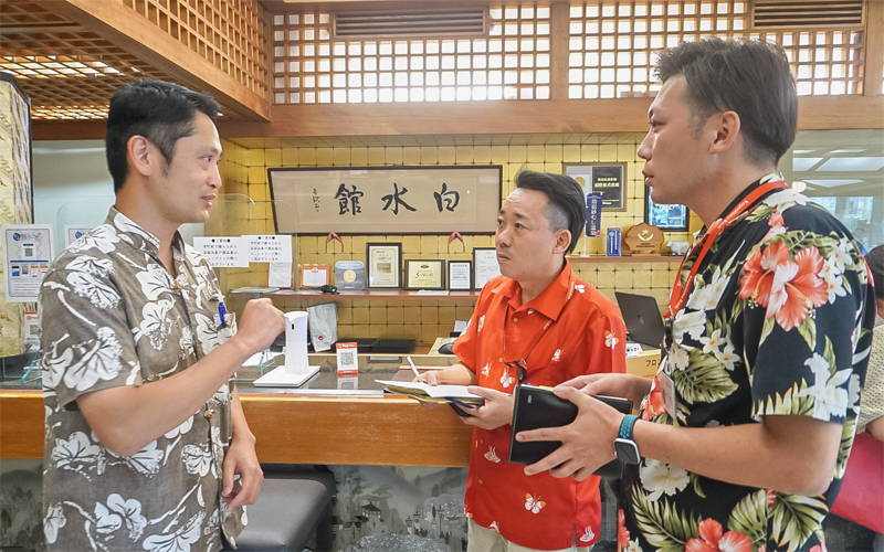 下竹原利彦社長(左)からフロント業務の状況を聞く山口佳史支店長(中央)と伊地知昭彦代理(8月10日、指宿白水館)