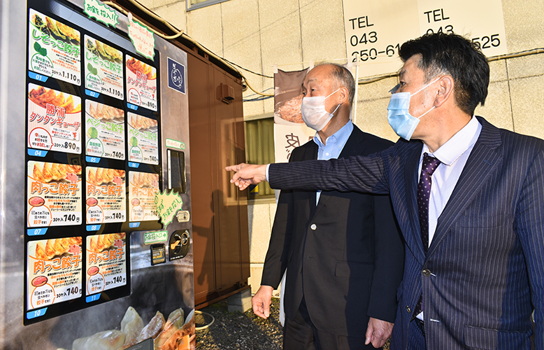 冷凍餃子の自販機の前で打ち合わせする高橋社長と島田氏(右、千葉市花見川区)
