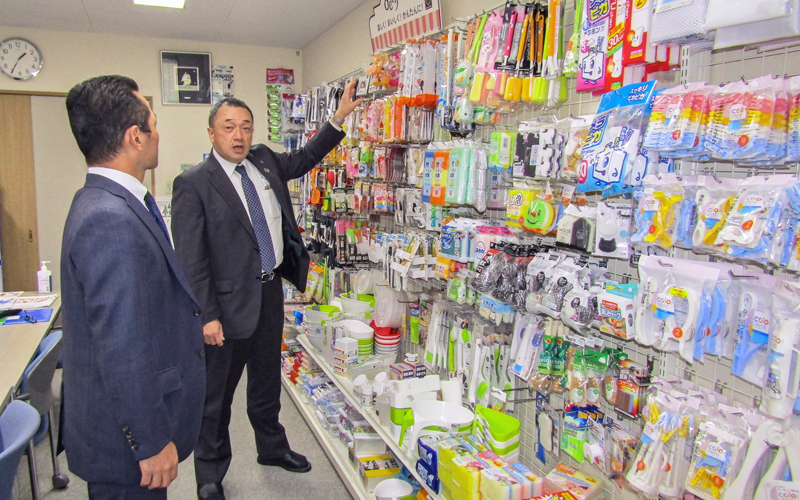 小久保工業所の小久保好章社長(右)から自社開発の100円ショップ向け商品の説明を聞く小松慎吾支店長(2021年12月16日)