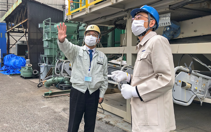 奥原祥司・コトブキ技研工業社長（左）から機械の説明を受ける西田仁支店長（２月２日）