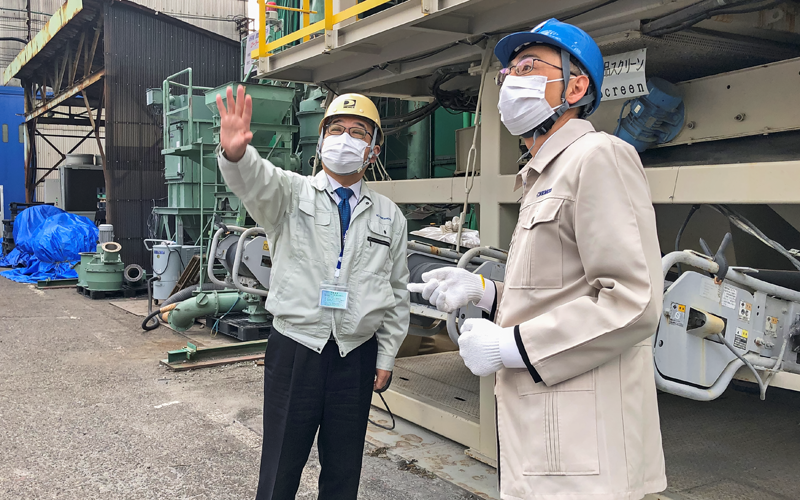 奥原祥司・コトブキ技研工業社長(左)から機械の説明を受ける西田仁支店長(2月2日)