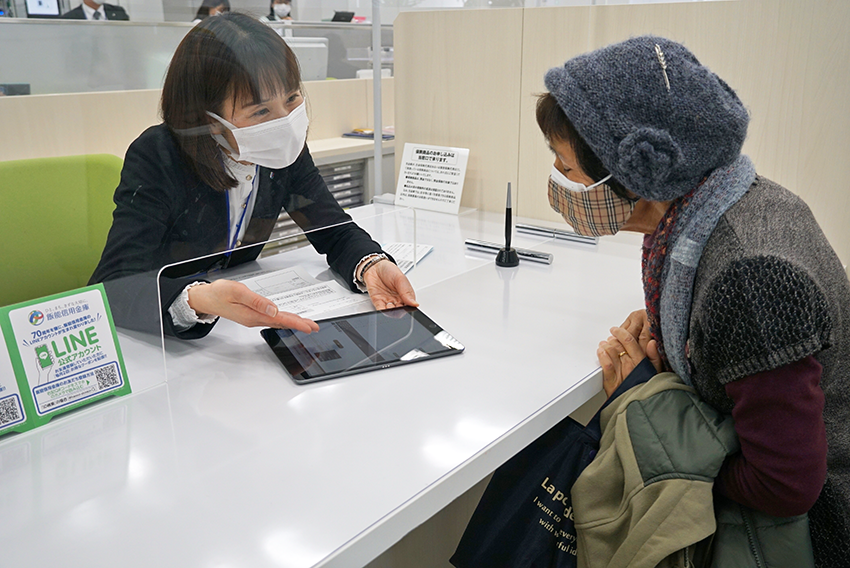 高齢者との共生がテーマに。写真はワクチン接種の予約を代行する女性職員（1月12日、飯能信金狭山支店・新狭山支店）