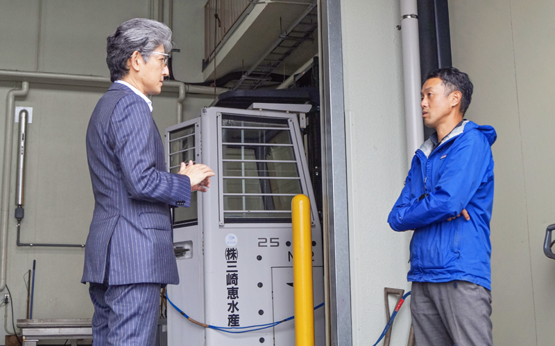 新装した省エネ設備の前で事業の展望を話し合う石井健太郎支店長(左)と石橋匡光社長(6月6日、三崎恵水産本社)