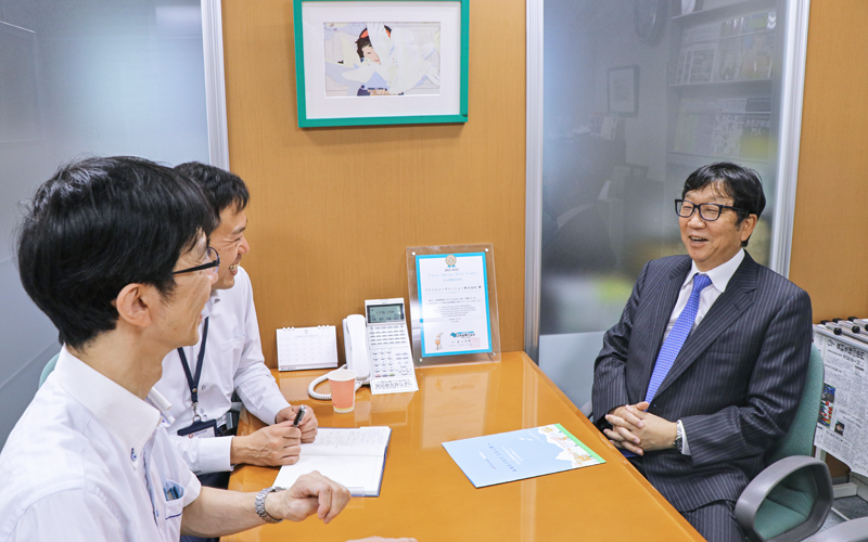 アミューズメント業を営むプライムコーポレーションの田村精一社長(右)と情報交換する鈴木章支店長(左奥)と朝井亮介副長(左手前、6月29日、プライムコーポレーション)