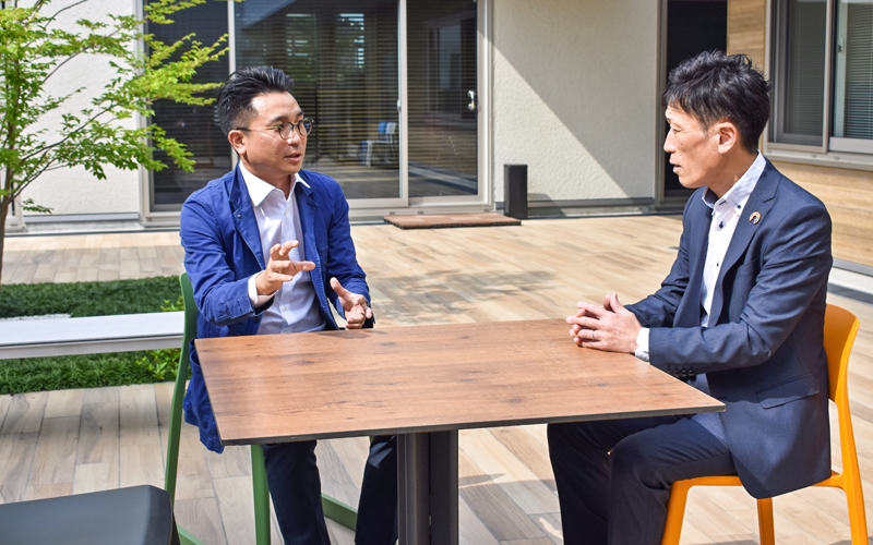 2021年に完成した藤井組新社屋の中庭テラスで藤井公嗣常務取締役(左)と情報交換する宮嶋秀輔支店長(7月20日、藤井組本社)