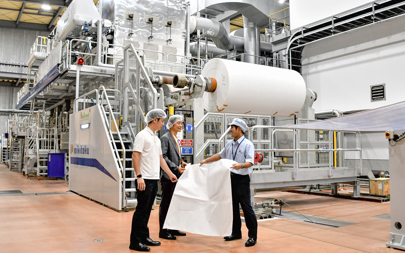 三木・三木特種製紙常務(右)から特殊紙の製造工程について説明を受ける伊予銀行川之江支店の次長(中)と担当者(8月29日、三木特種製紙)