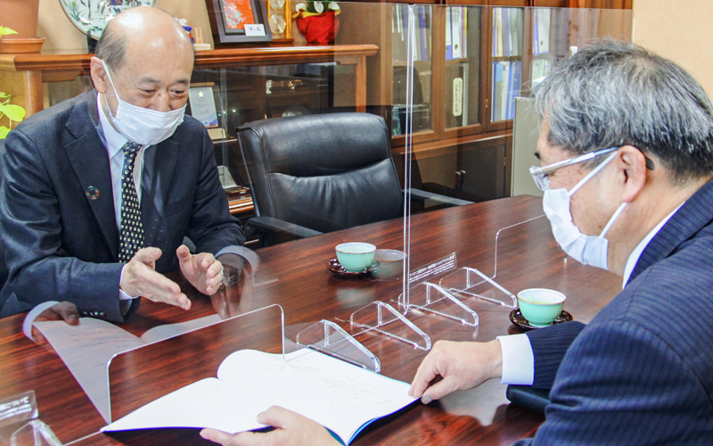 取引先の不動産賃貸業「平岸グランドビル」の中目明徳社長(左)を訪ねる佐藤仁寿支店長(3月14日、札幌市豊平区)