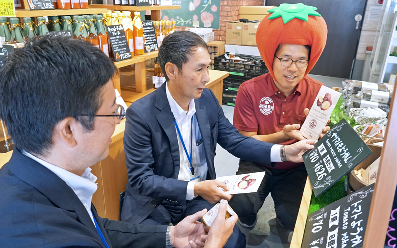 農業参入した三共木工の松本弓彦総務部長(右)と生産したサツマイモを使ったようかんについて情報交換する(左から)田中雄太次長と三田恒次支店長(6月8日、埼玉県川越市の@FARM FARMER'S MARKET)