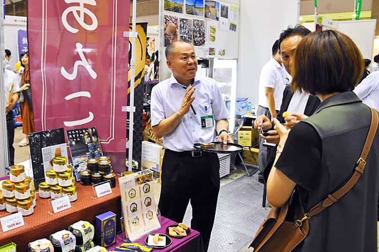 来場者に商品を紹介する池田屋商店の溝口統括部門長（左、8月23日、東京ビッグサイト）