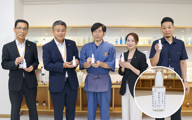 完成した化粧水「おんせんさん Mist」(写真右下)を手に持つ関係者ら(左から石野修・はくさん信金つるぎ営業部執行役員部長、西一嘉・はくさん信金米丸支店支店長、西山喜治・にしやま旅館6代目館主、ケイズ企画担当の岩本彰子氏、ケイズ開発担当の酒井純平氏、9月6日、ケイズ)