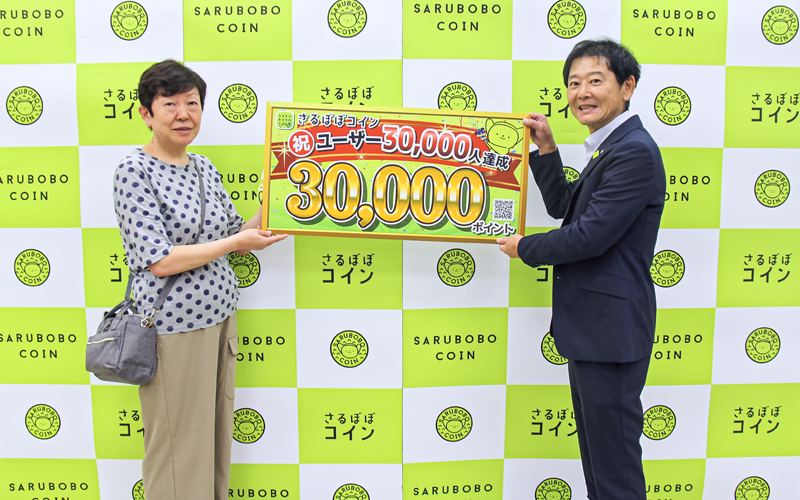 ユーザー登録３万人目の顧客にさるぼぼポイント３万円分を贈呈した（右は河瀬善博理事、神岡支店、飛騨信組提供）