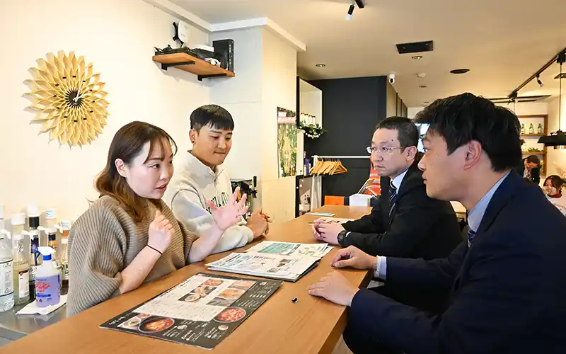 三重野課長(左から3人目)、阿南課長代理(同4人目)と相談するシンさん夫妻(1月15日、大分市内)