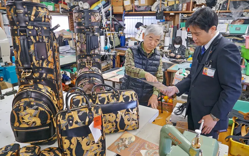 小山ゴルフバック製作所の小山光夫代表(左)と海外販路について情報交換する山口直史支店長(1月25日、さいたま市南区)