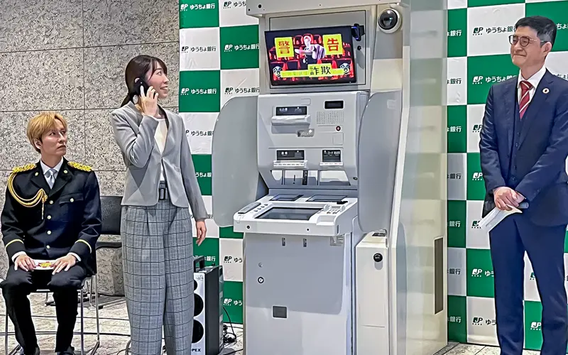 ATM前でAIが通話動作を確認すると、ATM上部のデジタルサイネージで橘慶太・警察庁特別防犯支援官（左）による警告動画と音声が流れた（２月20日、大手町プレイス）