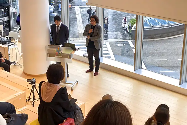 参加者に説明する二宮課長(左)と伊藤係長(2月26日、QUESTION)