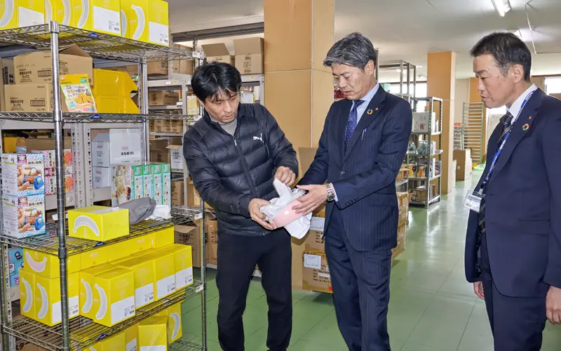 花岡商店の花岡智之社長（左）から売れ筋のベビー用品について説明を受ける橋本勝彦支店長（中央）と片山哲也営業推進部部付部長（２月８日、北島町）