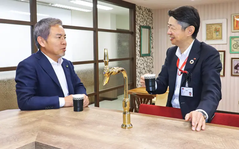 ひいらぎホールディングス本社内のバーカウンターで談笑する柊崎庄二社長(左)と安水学支店長(3月25日)