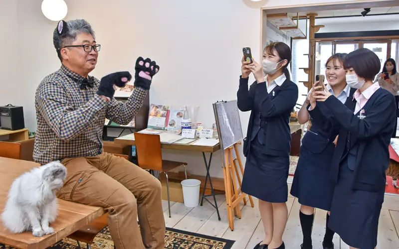 ねこルーム設計施工の「きじとら」岡田誠・代表取締役(左)を撮影するよなっこ通信の運営メンバー(5月16日、米子市)