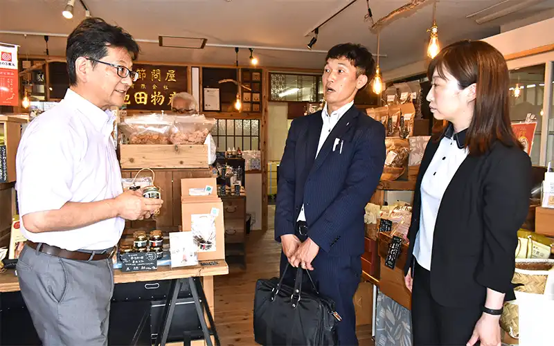 (左から)「かつお節にかけるたれ」を手に売れ行きなどを説明する池田社長、同信金新高島平支店の藤沼克仁係長とすがも事業創造センターの長島史織係長(6月6日、埼玉県和光市のかつをぶし池田屋)